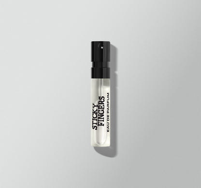 Small perfume bottle labeled 'Sticky Fingers' by the Rolling Stones on a light gray background