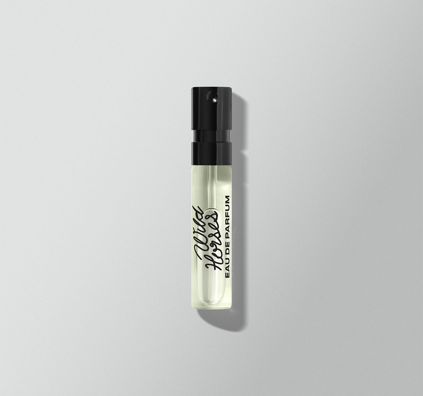 Small perfume bottle with black cap on a light gray background