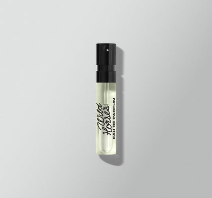 Small perfume bottle with black cap on a light gray background